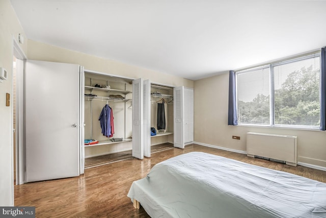 2939 Van Ness St NW Unit 608, Washington, DC 20008 - bedroom with radiator, multiple closets, wood finished floors, and baseboards