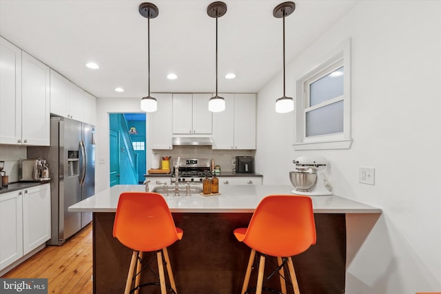 1620 E Berks St, Philadelphia, PA 19125 - kitchen with appliances with stainless steel finishes, under cabinet range hood, white cabinets, a kitchen breakfast bar, and backsplash