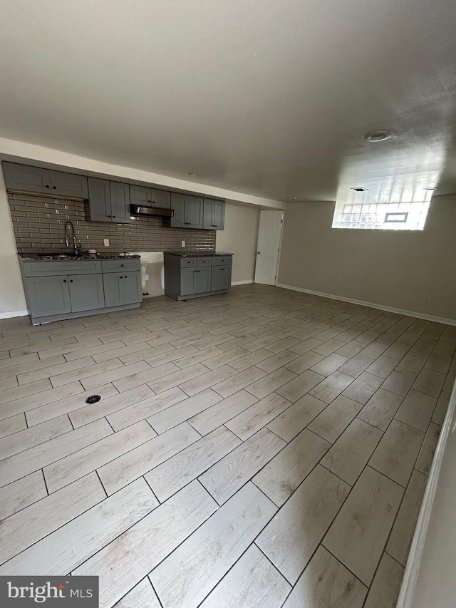 5221 N 8th St, Philadelphia, PA 19120 - kitchen featuring gray cabinetry, under cabinet range hood, a sink, wood finish floors, and baseboards
