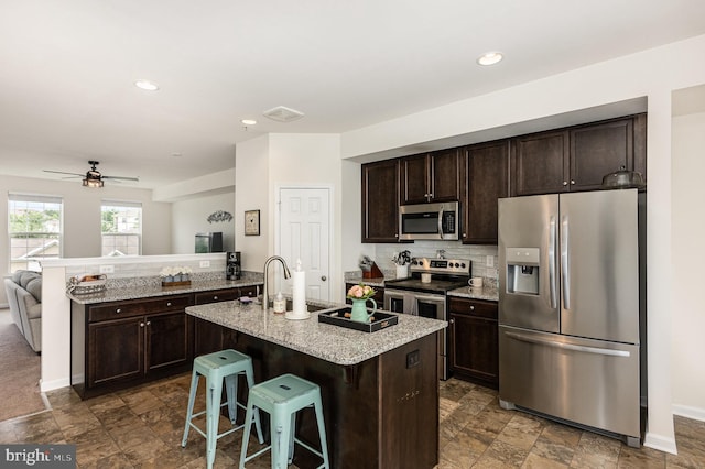 418 Charlestown Crossing Blvd, North East, MD 21901 - kitchen with stainless steel appliances, dark brown cabinets, a peninsula, a breakfast bar area, and light stone countertops
