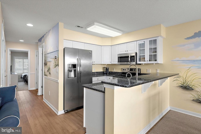 205 125th St Unit M253H8, Ocean City, MD 21842 - kitchen with appliances with stainless steel finishes, a peninsula, glass insert cabinets, baseboards, and light wood-style floors