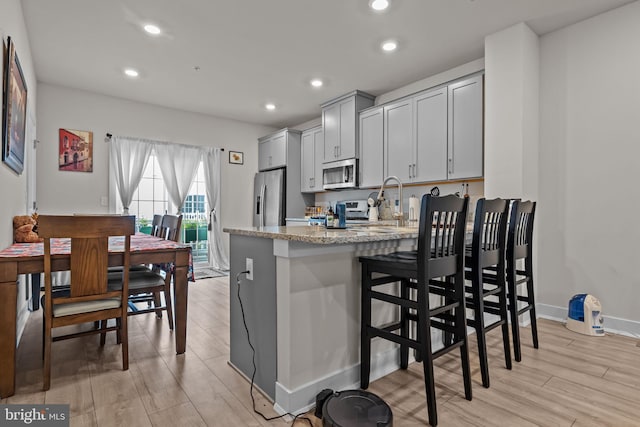 108 Annapolis St, Bensalem, PA 19020 - kitchen featuring stainless steel appliances, a peninsula, light stone counters, light wood-style floors, and recessed lighting