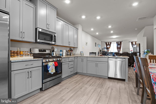 108 Annapolis St, Bensalem, PA 19020 - kitchen featuring appliances with stainless steel finishes, gray cabinets, open floor plan, a peninsula, and light wood-style floors