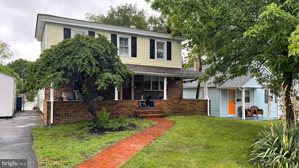 228 N Railroad Ave, Wyoming, DE 19934 - view of front of house featuring covered porch, a front yard, brick siding, and a chimney