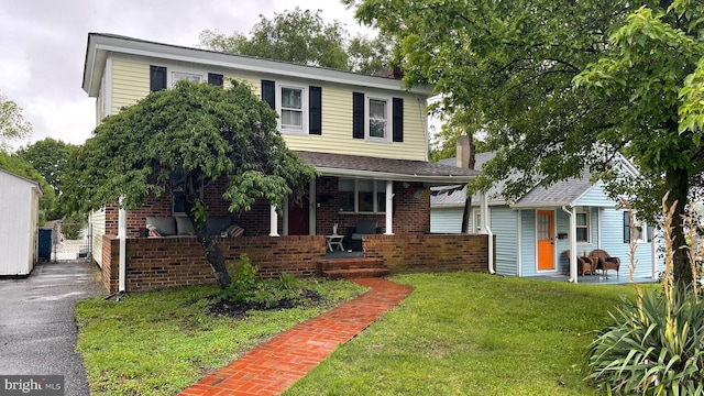 228 N Railroad Ave, Wyoming, DE 19934 - view of front of house featuring covered porch, a front yard, brick siding, and a chimney