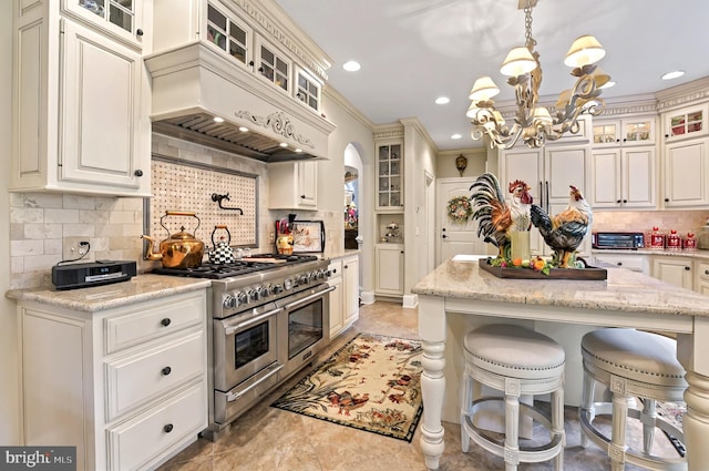 1780 Eliza Way, Mechanicsburg, PA 17050 - kitchen featuring range with two ovens, tasteful backsplash, arched walkways, a breakfast bar, and a chandelier