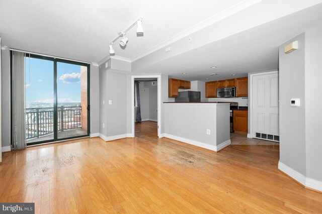 414 Water St Unit 2805, Baltimore, MD 21202 - unfurnished living room featuring light wood finished floors, baseboards, expansive windows, rail lighting, and crown molding