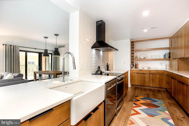 3801 Canterbury Rd Unit 705, Baltimore, MD 21218 - kitchen featuring wall chimney exhaust hood, brown cabinetry, a sink, wood finished floors, and light countertops