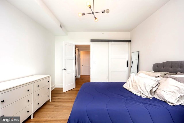 3801 Canterbury Rd Unit 705, Baltimore, MD 21218 - bedroom featuring light wood-type flooring, a chandelier, and baseboards