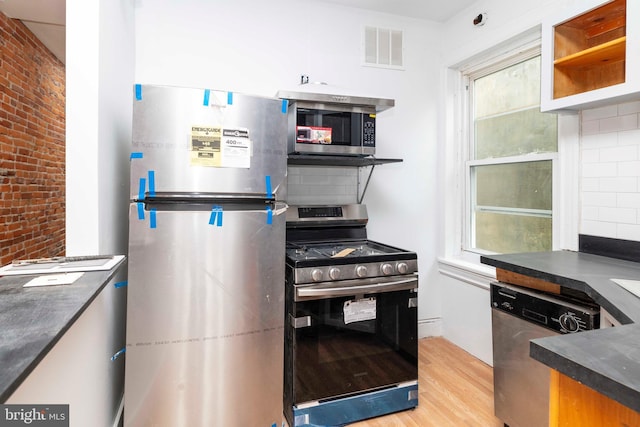 2308 N Park Ave, Philadelphia, PA 19132 - kitchen featuring stainless steel appliances, light wood-type flooring, dark countertops, and decorative backsplash