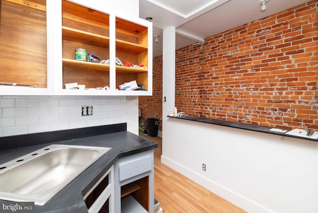 2308 N Park Ave, Philadelphia, PA 19132 - kitchen with tasteful backsplash, light wood-style flooring, dark countertops, a sink, and baseboards
