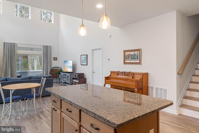 35031 Dundee St Unit 6, Frankford, DE 19945 - kitchen featuring light wood-style flooring, open floor plan, high vaulted ceiling, a kitchen island, and dark stone counters