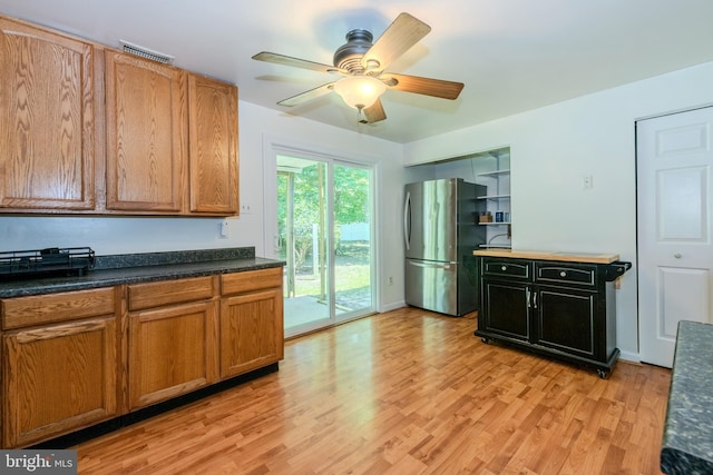 18552 Three Notch Rd, Lexington Park, MD 20653 - kitchen with freestanding refrigerator, light wood finished floors, ceiling fan, dark countertops, and brown cabinetry