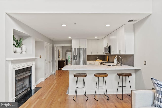1406 Corcoran St NW Unit D, Washington, DC 20009 - kitchen featuring stainless steel appliances, a peninsula, white cabinetry, tasteful backsplash, and recessed lighting