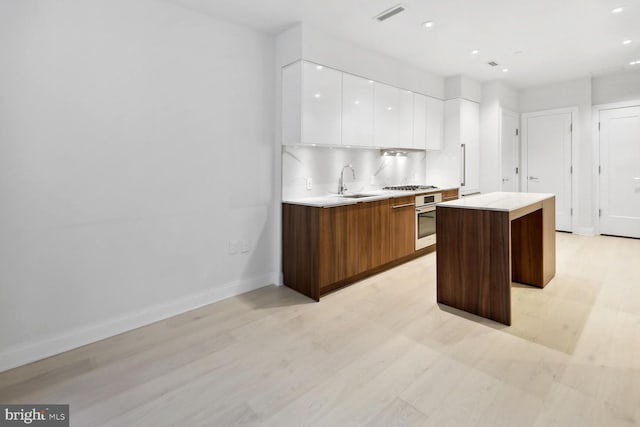 1427 Rhode Island Ave NW Unit 202, Washington, DC 20005 - kitchen with appliances with stainless steel finishes, modern cabinets, a center island, white cabinetry, and light countertops