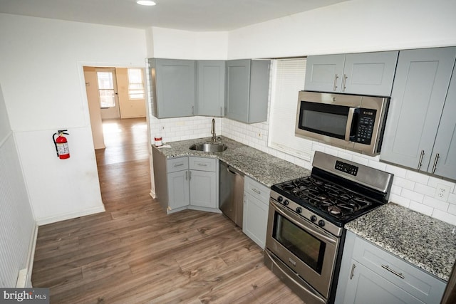 1011 Andrews Ave, Darby, PA 19023 - kitchen with stainless steel appliances, a sink, light wood-style flooring, and light stone countertops
