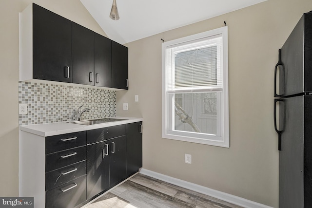 11174 Glade Dr, Reston, VA 20191 - kitchen featuring dark cabinetry, freestanding refrigerator, a sink, tasteful backsplash, and light wood-style flooring
