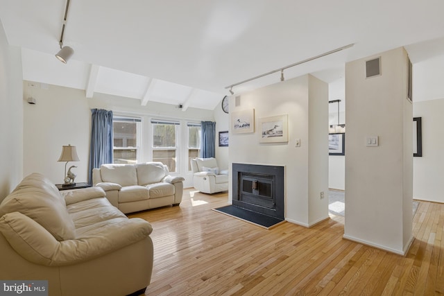 11174 Glade Dr, Reston, VA 20191 - living room featuring track lighting, light wood-type flooring, a glass covered fireplace, and baseboards