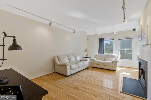 11174 Glade Dr, Reston, VA 20191 - living area with track lighting, light wood-type flooring, a fireplace with flush hearth, and baseboards