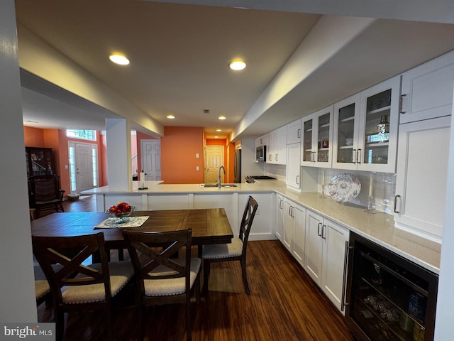 132 Seabright Way Unit D5, Rehoboth Beach, DE 19971 - kitchen featuring beverage cooler, a sink, dark wood-type flooring, glass insert cabinets, and a peninsula