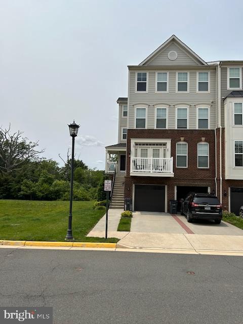 43405 Town Gate Sq, Chantilly, VA 20152 - view of front facade featuring driveway, an attached garage, a front lawn, brick siding, and stairway