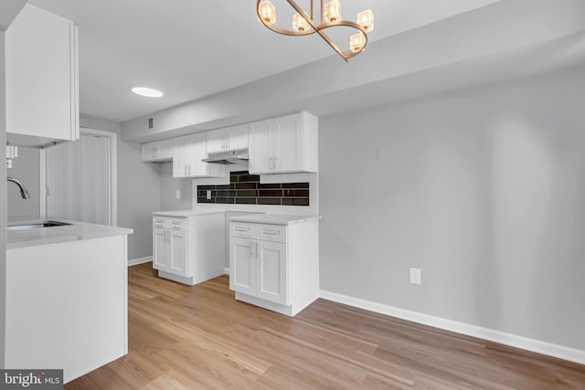 31 Ewing Dr Unit C, Reisterstown, MD 21136 - kitchen featuring under cabinet range hood, white cabinetry, light wood finished floors, and backsplash