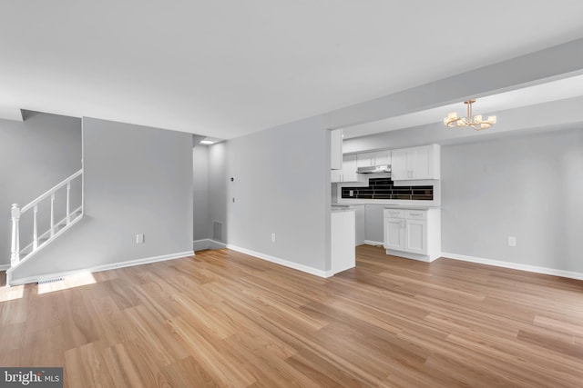 31 Ewing Dr Unit C, Reisterstown, MD 21136 - unfurnished living room featuring a chandelier, light wood-type flooring, and stairway