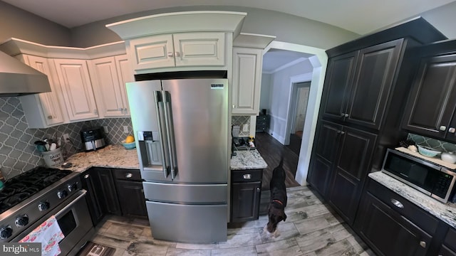 731 W Main St, Leesport, PA 19533 - kitchen featuring stainless steel appliances, dark cabinetry, tasteful backsplash, light stone countertops, and wall chimney exhaust hood