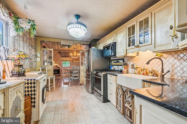 947 Martin Rd, Baltimore, MD 21221 - kitchen featuring appliances with stainless steel finishes, a chandelier, cream cabinets, decorative backsplash, and light wood-type flooring