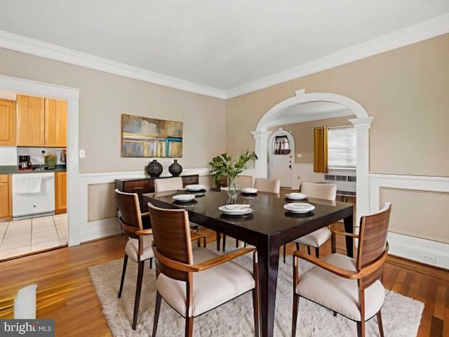 2707 Kildaire Dr, Baltimore, MD 21234 - dining area with arched walkways, decorative columns, light wood-type flooring, crown molding, and a wainscoted wall