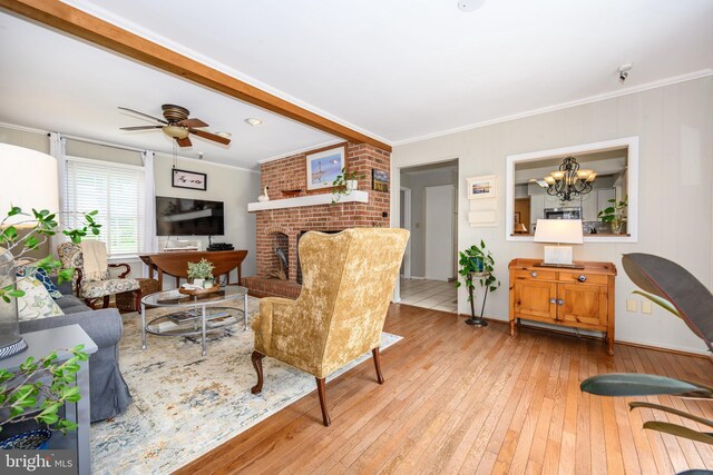 12 Hatsawap Rd, Cambridge, MD 21613 - living area featuring light wood-style flooring, ornamental molding, ceiling fan, a chandelier, and a fireplace