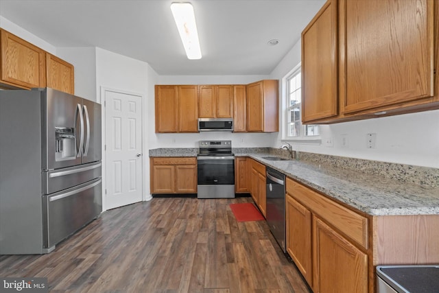 605 Red Timber Ln, Smyrna, DE 19977 - kitchen featuring appliances with stainless steel finishes, dark wood finished floors, light stone countertops, and brown cabinets