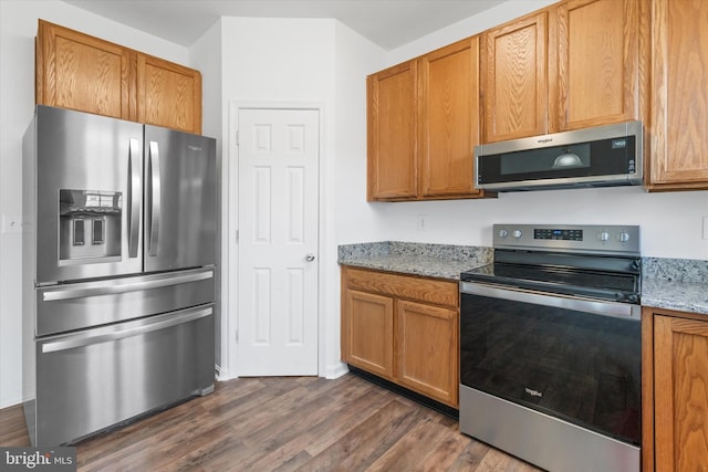 605 Red Timber Ln, Smyrna, DE 19977 - kitchen featuring appliances with stainless steel finishes, dark wood-style floors, light stone countertops, and brown cabinetry