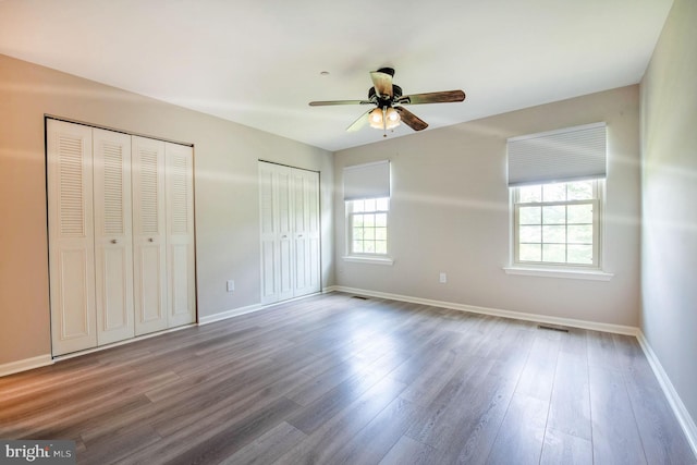691 Metro Ct Unit 9, West Chester, PA 19380 - unfurnished bedroom with multiple closets, wood finished floors, baseboards, and a ceiling fan