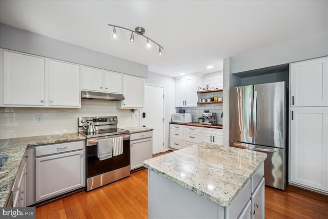 19112 Gunnerfield Ln, Germantown, MD 20874 - kitchen featuring stainless steel appliances, under cabinet range hood, decorative backsplash, light wood finished floors, and a kitchen island
