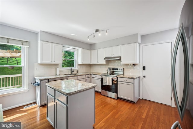 19112 Gunnerfield Ln, Germantown, MD 20874 - kitchen featuring stainless steel appliances, a sink, under cabinet range hood, decorative backsplash, and light wood finished floors