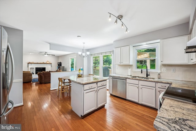 19112 Gunnerfield Ln, Germantown, MD 20874 - kitchen with stainless steel appliances, a sink, a chandelier, light stone counters, and a brick fireplace
