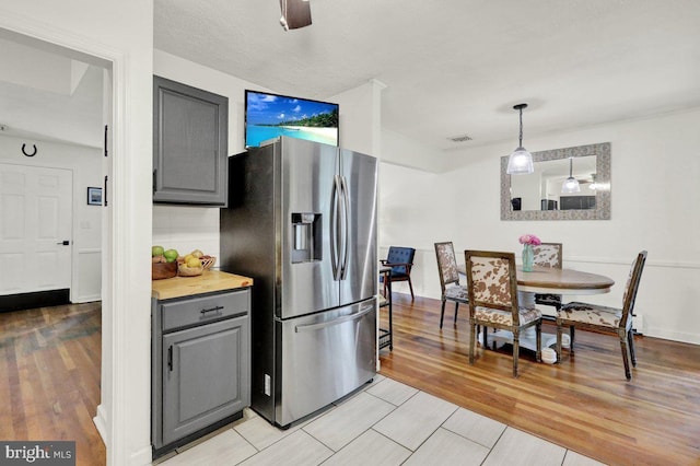 102 Radcliffe Ave, Reading, PA 19609 - kitchen with stainless steel refrigerator with ice dispenser, gray cabinetry, light wood-style flooring, light countertops, and hanging light fixtures