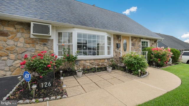 126 Heartwood Rd, Levittown, PA 19056 - doorway to property featuring stone siding, a wall mounted air conditioner, and a shingled roof