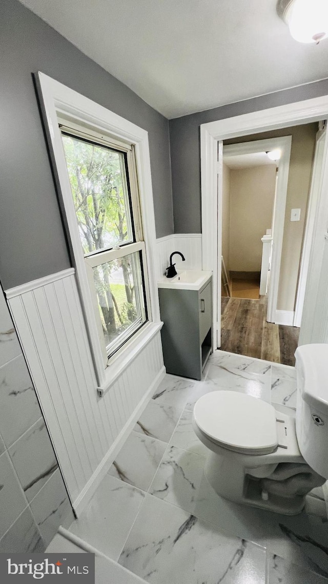 1105 N Chestnut St, Paulsboro, NJ 08066 - half bath featuring marble look tile flooring, toilet, wainscoting, and vanity