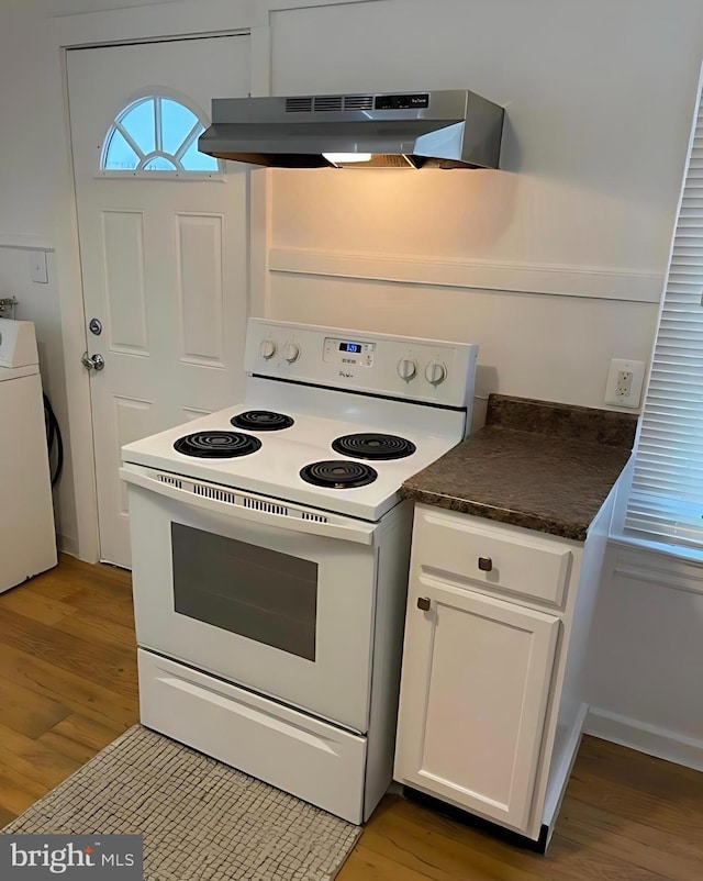 1105 N Chestnut St, Paulsboro, NJ 08066 - kitchen with white electric range oven, under cabinet range hood, washer / clothes dryer, wood finished floors, and dark countertops