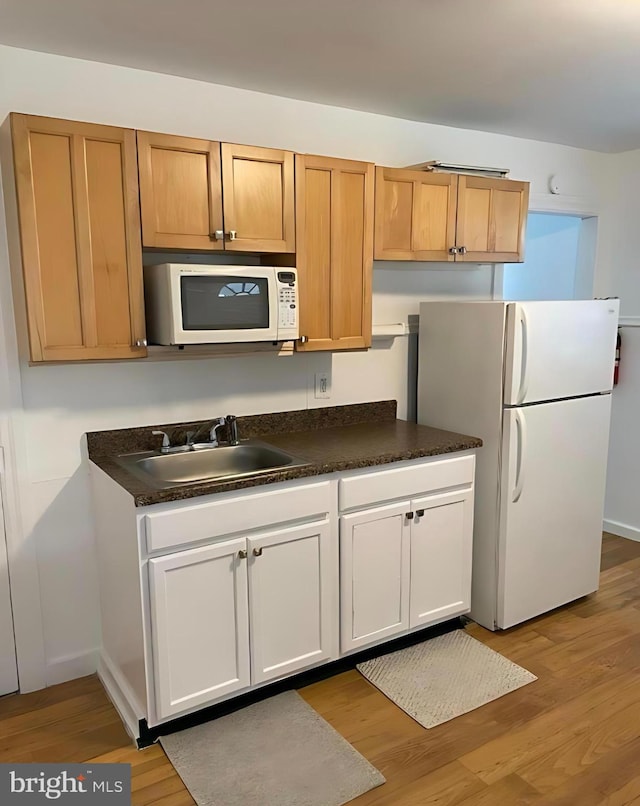1105 N Chestnut St, Paulsboro, NJ 08066 - kitchen with white appliances, a sink, light wood finished floors, dark countertops, and baseboards