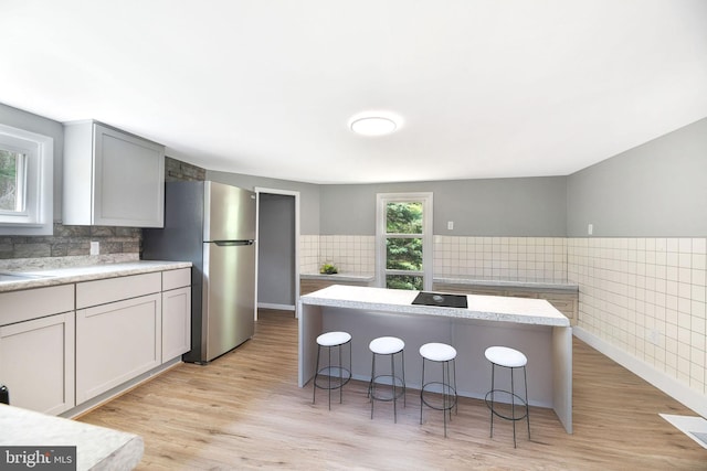 223 One Mile Run Rd, Philipsburg, PA 16866 - kitchen with freestanding refrigerator, light countertops, a breakfast bar, tile walls, and light wood-style floors