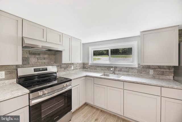 223 One Mile Run Rd, Philipsburg, PA 16866 - kitchen with stainless steel electric range oven, a sink, under cabinet range hood, light countertops, and decorative backsplash