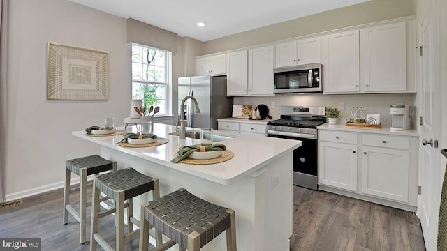 2041 Gregory Dr, Allentown, PA 18103 - kitchen with appliances with stainless steel finishes, a sink, wood finished floors, white cabinets, and a kitchen bar