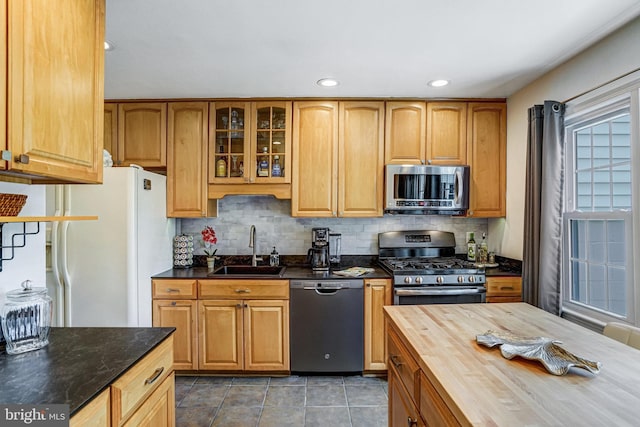 5901 Wivenhoe Ct, Alexandria, VA 22315 - kitchen with appliances with stainless steel finishes, a sink, wooden counters, decorative backsplash, and glass insert cabinets