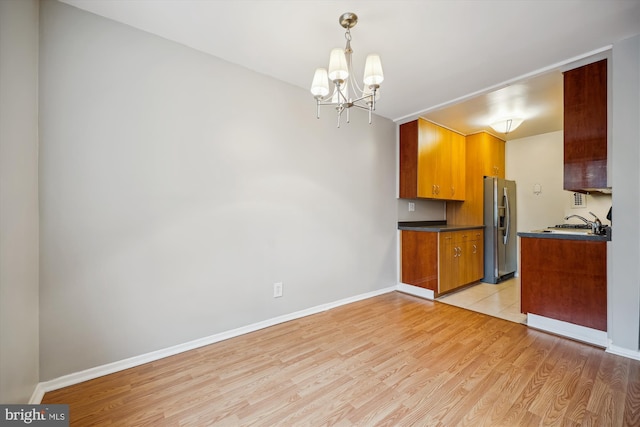 8601 Manchester Rd Unit 319, Silver Spring, MD 20901 - kitchen featuring stainless steel refrigerator with ice dispenser, dark countertops, light wood-style flooring, a chandelier, and brown cabinets
