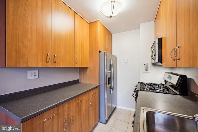 8601 Manchester Rd Unit 319, Silver Spring, MD 20901 - kitchen featuring appliances with stainless steel finishes, light tile patterned floors, brown cabinetry, and dark countertops