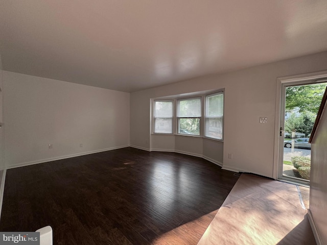 225 N New St, Dover, DE 19904 - unfurnished living room with dark wood-style floors and baseboards