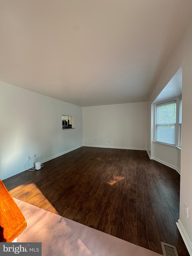 225 N New St, Dover, DE 19904 - unfurnished living room with dark wood-style flooring and baseboards